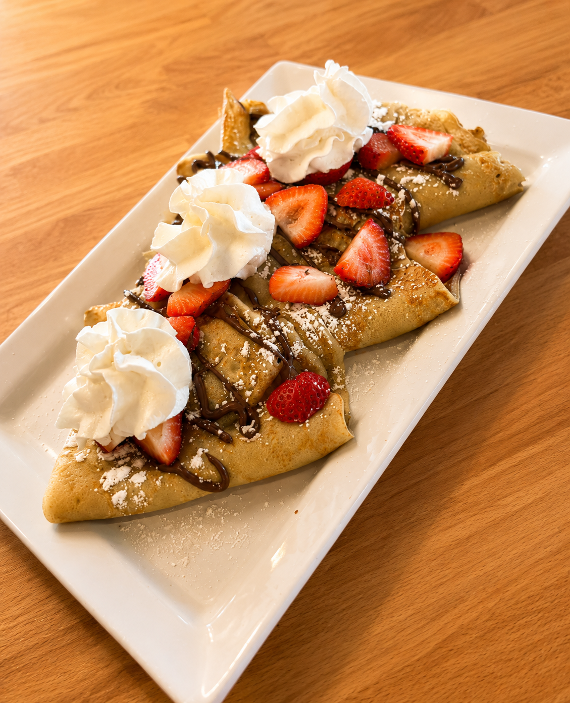 Nutella crepe topped with fresh strawberries, powdered sugar and whipped cream