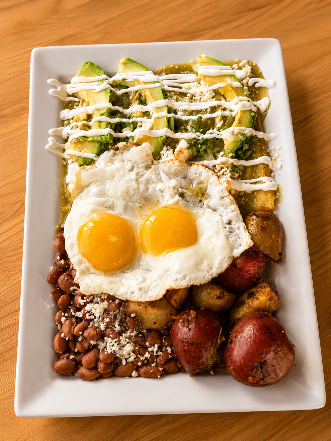 Chilaquiles verdes with fried eggs, roasted potatoes and beans